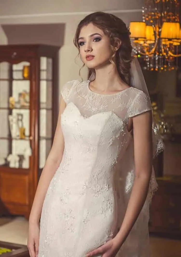 ---Elegant ivory wedding dress for a romantic woman made of lace with illusions in the decollette and short sleeves--